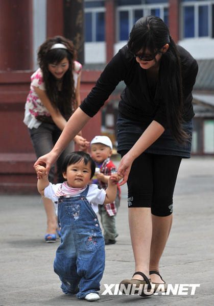 5月11日，已经满岁的“地震宝宝”们在妈妈的搀扶下走路。