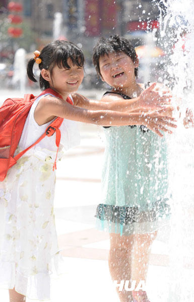 6月24日，孩子们在郑州市二七广场的喷泉旁消暑。